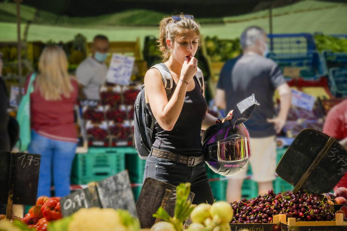 Une fille devant un stand de fruits et légumes